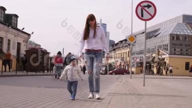 年轻的美女和她的小儿子正走在城市历史中心的步行街上。
